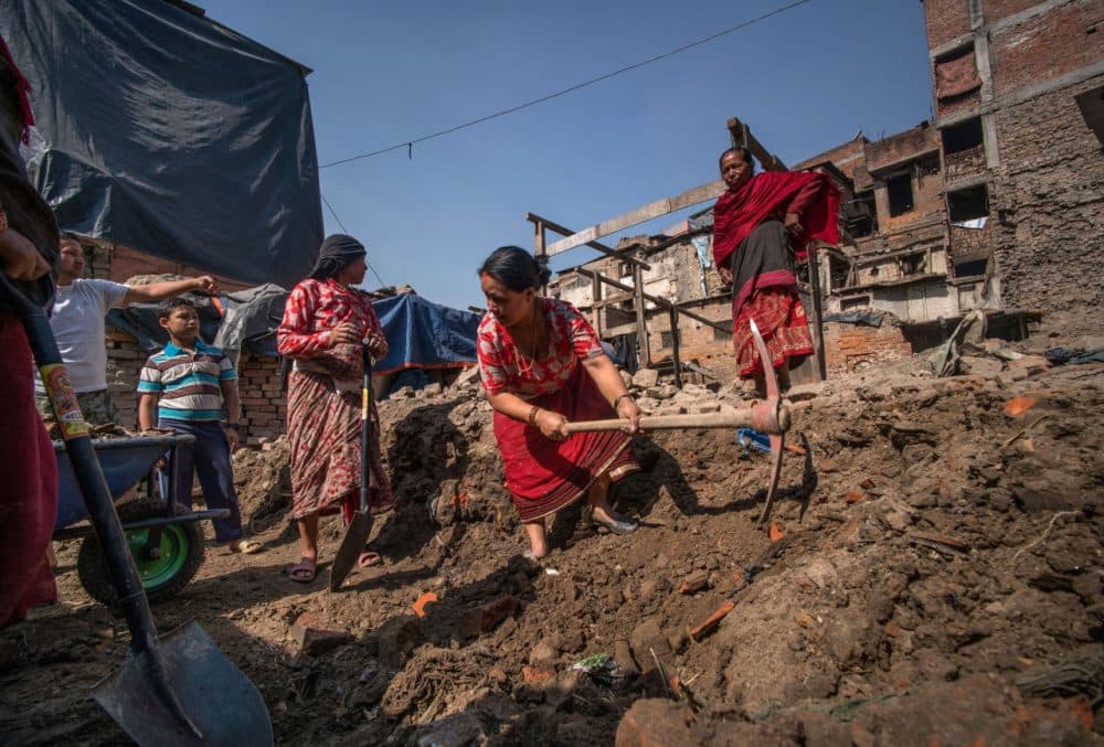 Bidhya Laxmi Prajapati, 45, works with a pickaxe as she clears debris at her former house  damaged during the April 2015 earthquake, together with family and neighbors on April 24, 2016 in Kathmandu, Nepal. Bidhya recently started rebuilding her house which collapsed during last year's earthquake after deciding not to wait any further for compensation promised by the government.  A 7.8-magnitude earthquake struck Nepal close to midday on April 25 lasts year. It was Nepal's worse earthquake in history as an estimated 9,000 people died and countless towns and villages across central Nepal were destroyed. Based on reports, the government promised 2,000USD to affected households but has only paid out a fraction of the amount so far and an estimated 660,000 families are still living in sub-standard temporary shelters or unsafe accommodation one year later.  (Tom Van Cakenberghe/Getty Images)