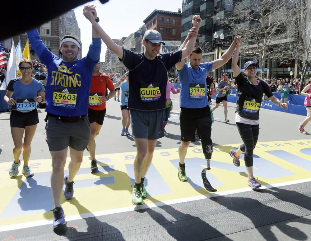 Boston Marathon bombing survivor and amputee Patrick Downes, second from left, crosses the finish line with companions Monday. (Elise Amendola/AP)