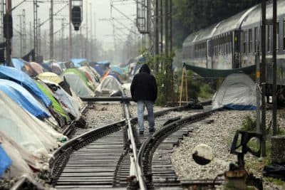 A man walks on the rail tracks of a train station turned into a makeshift camp crowded by migrants and refugees, at the northern Greek border point of Idomeni, Greece, Friday, April 29, 2016. Many thousands of migrants remain at the Greek border with Macedonia, hoping that the border crossing will reopen, allowing them to move north into central Europe. (AP Photo/Gregorio Borgia)