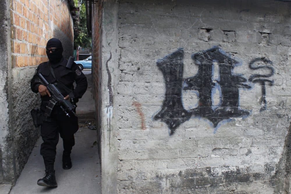In this April 5, 2016 photo, a masked and armed policeman patrols a gang controlled neighborhood in San Salvador, El Salvador. Hyper-violent gangs declared open-season on police in this Central American nation in response to a government crackdown that began last year. Justice and Security Minister Mauricio Ramirez Landaverde, who was national police director until January, acknowledged that security forces are vulnerable. (AP Photo/Alex Peña)