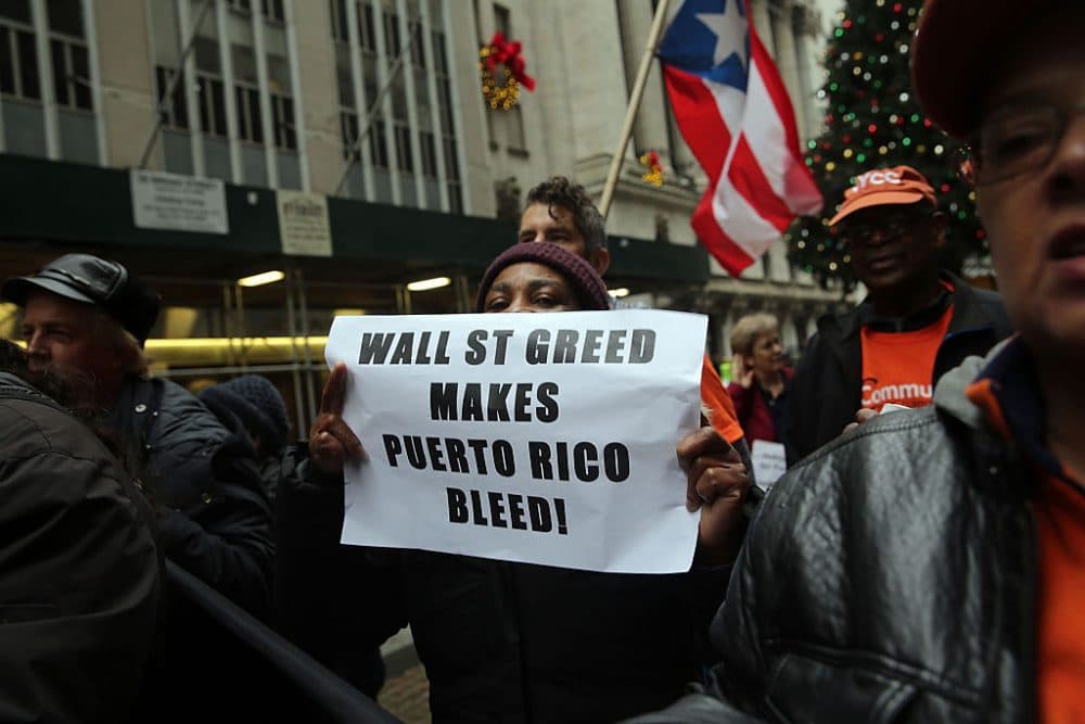 People protest outside of Wall Street against cutbacks and austerity measures forced onto the severely indebted island of Puerto Rico on December 2, 2015 in New York City. Puerto Rico made a $355 million payment on Tuesday on its bond debt to stave off a default. Officials have warned that the commonwealth's fiscal position remain dire. (Spencer Platt/Getty Images)