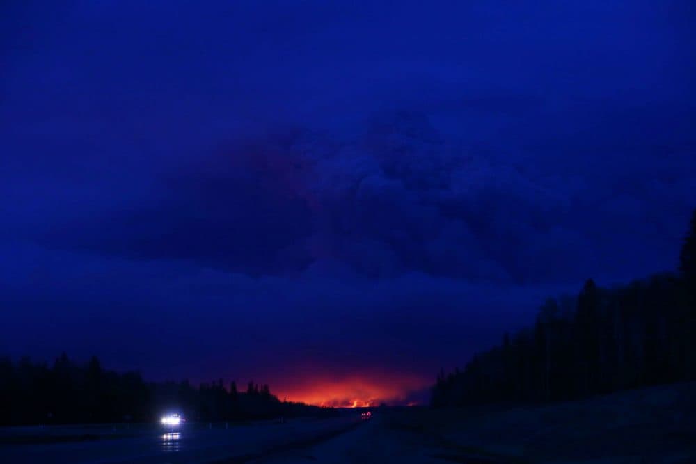 A plume of smoke hangs in the air as forest fires rage on in the distance in Fort McMurray, Alberta on May 4, 2016.
Numerous vehicles can be seen abandoned on the highways leading from the raging forest fires in Fort McMurray and neighbouring communities have banded together to offer support in the form of food, water, and gasoline.  (Cole Burston/AFP/Getty Images)