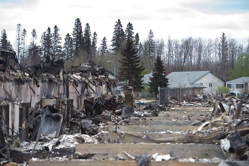 Untouched homes are seen in the background as others destroyed by fire are seen in the foreground in the Abasands neighbourhood during a media tour of the fire-damaged city of Fort McMurray, Alberta, May 9, 2016. (JONATHAN HAYWARD/AFP/Getty Images)