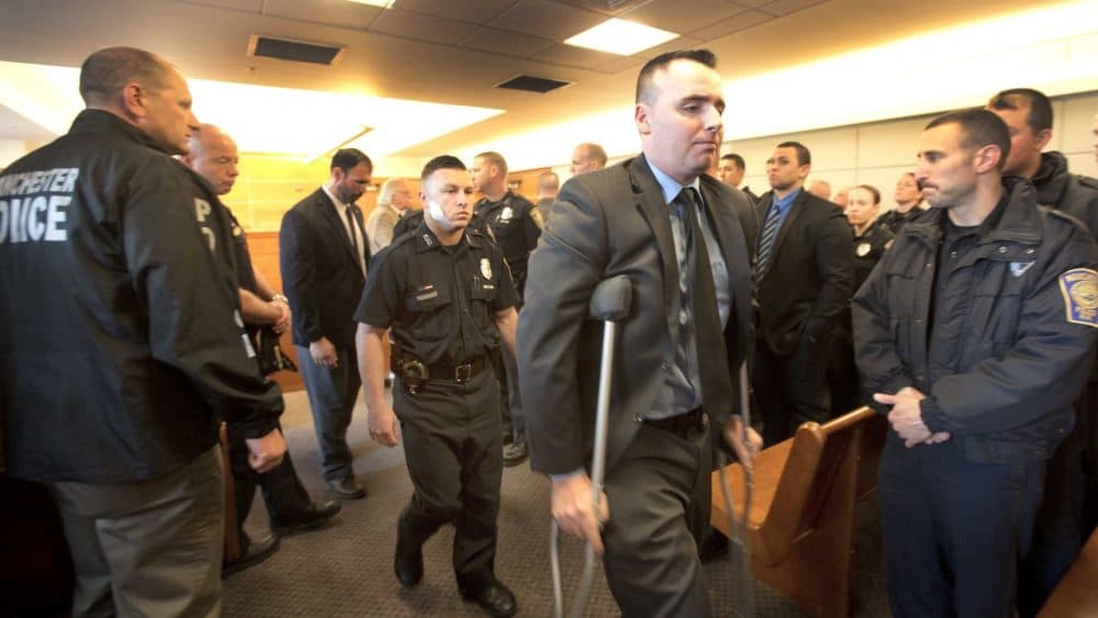 Matthew O'Connor, on crutches, and Ryan Hardy, behind him, leave the courtroom in Manchester, N.H. on Monday after attending a hearing for Ian MacPherson. MacPherson is charged with shooting both officers last week. (Jim Cole/AP, Pool)