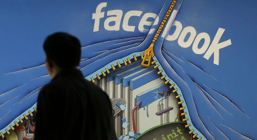 In this June 11, 2014 photo, a man walks past a mural in an office on the Facebook campus in Menlo Park, Calif. On Thursday, May 12, 2016, Facebook pulled back the curtain on how its Trending Topics feature works, a reaction to a report that suggested Facebook downplays conservative news subjects. (Jeff Chiu/AP)
