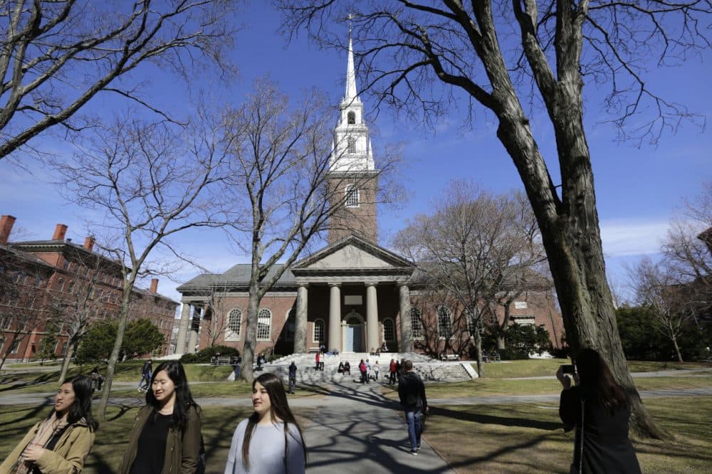 In this March 13, 2016 photo, people walk near Memorial Church on the campus of Harvard University in Cambridge, Mass. The university's first female president, Drew Faust, announced Friday, May 6, 2016, that students who join Harvard's male-only social clubs won't be able to serve as sports captains or leaders of other campus groups starting in fall 2017. (Steven Senne/AP)