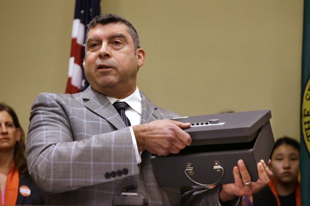 A Seattle public health official demonstrates the use of a gun lock box during a news conference on Jan. 21. (Elaine Thompson/AP)