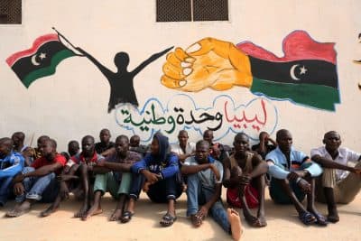 Illegal migrants sit in front of a painted wall on May 19, 2016 at the Abu Salim detention centre in the Libyan capital Tripoli during a visit of United Nations' special envoy to Libya. (Mahmud Turkia/AFP/Getty Images)