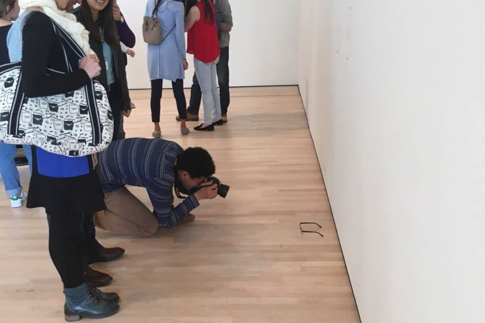A man kneels down to take a photograph of a pair of glasses left behind by 16-year-old Kevin Nguyen at the San Francisco Museum of Modern Art in San Francisco, California. (Courtesy/Kevin Nguyen)