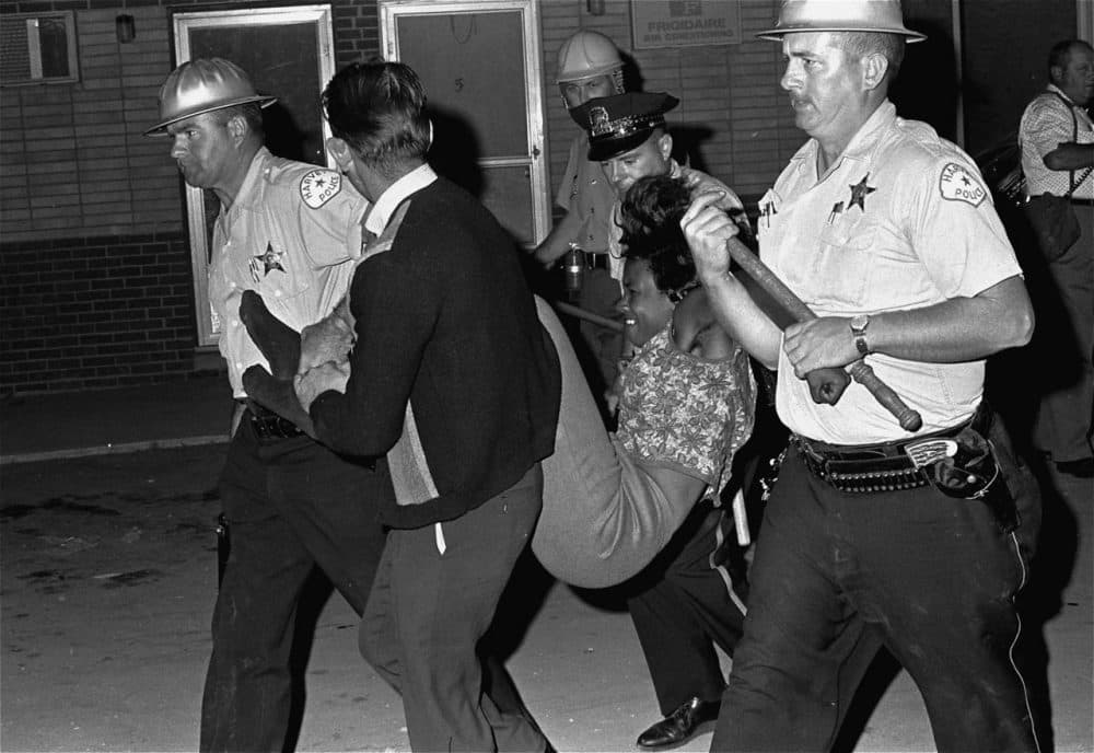 A woman who stayed at the riot scene in Dixmoor, Illinois in August 1964 is carried to a police van. More than a score were arrested. (AP)