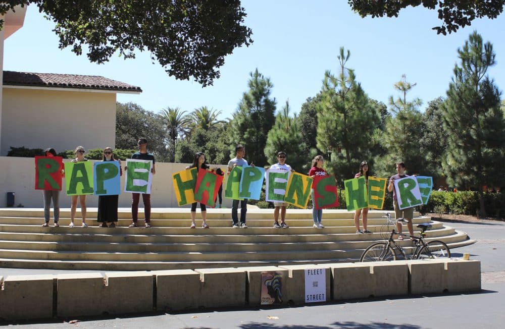 In this Sept. 16, 2015 photo provided by Tessa Ormenyi, students hold up a sign about rape at White Plaza during New Student Orientation on the Stanford University campus in Stanford, California. (Tessa Ormenyi via AP)