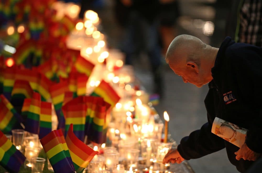 A man places a candle at an impromptu memorial set up in Sydney on Monday following the Orlando attack. Australian Prime Minister Malcolm Turnbull said that the Orlando mass shooting was &quot;an attack on all of us, on all our freedoms, the freedom to gather together, to celebrate, to share time with friends.&quot; (Rick Rycroft/AP)