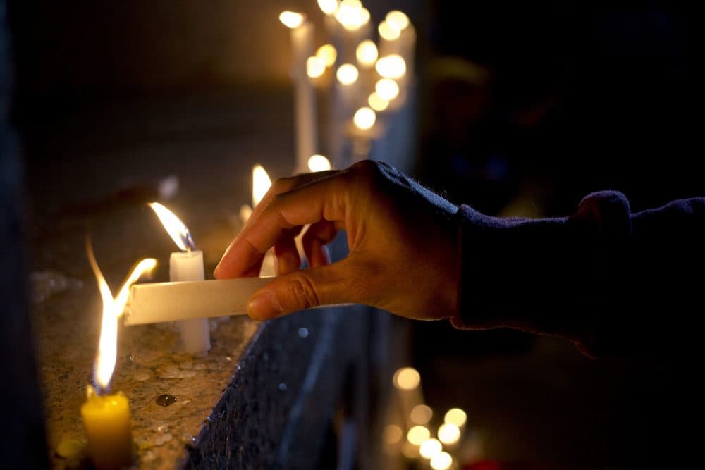 A man lights a candle during a vigil in front of the U.S. embassy in Santiago, Chile to remember the victims. (Esteban Felix/AP)