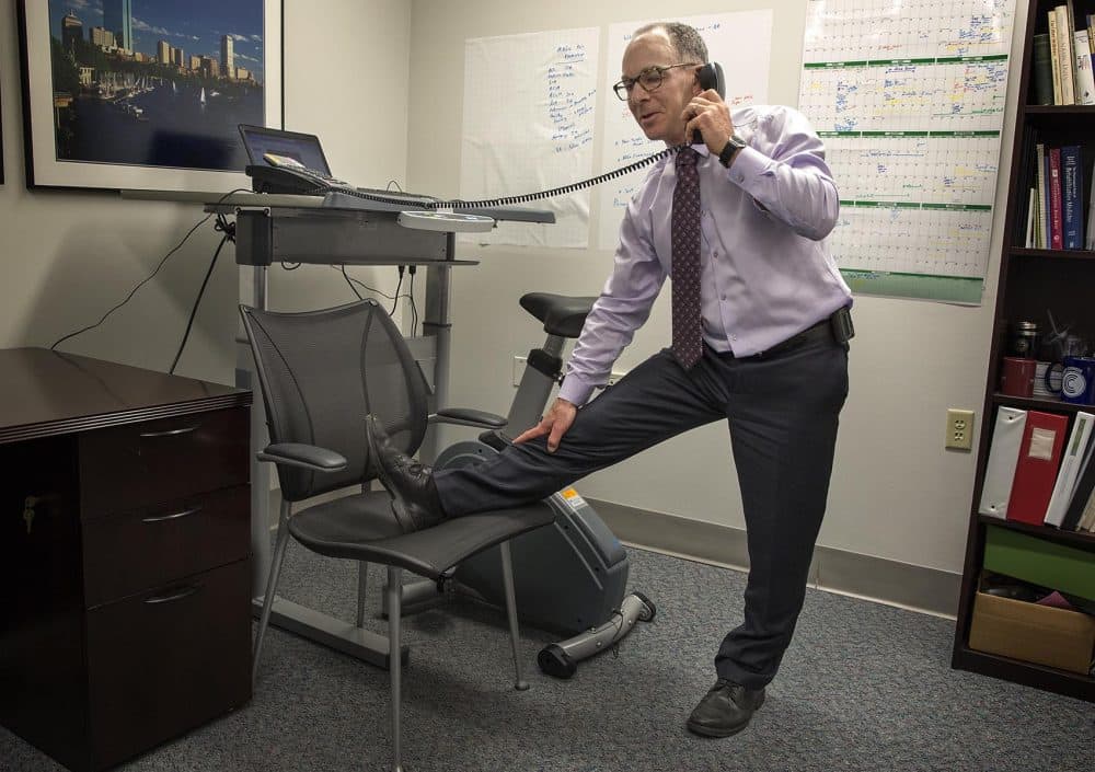 Dr. Eddie Phillips stretches as he talks on the phone at his office at the VA Boston Healthcare System. (Robin Lubbock/WBUR)