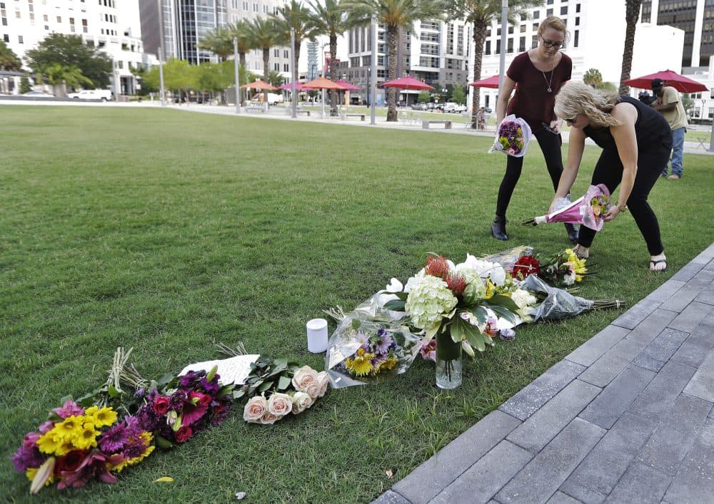 Two women place flowers for the victims of the fatal shootings at Pulse Orlando nightclub at a makeshift memorial in Orlando, Fla. on Monday. (Chris O'Meara/AP)