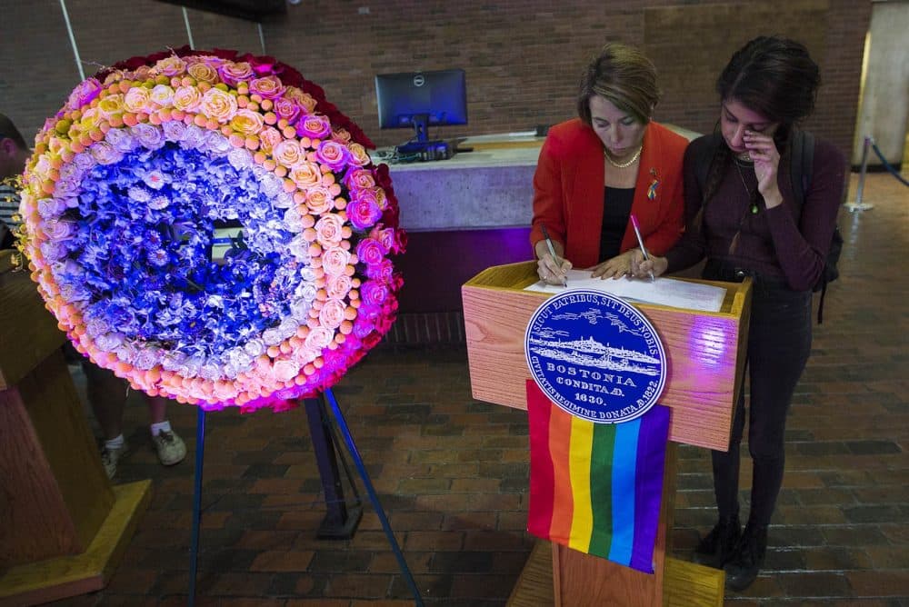 Massachusetts Attorney General Maura Healey signs the condolence book inside City Hall with Maya Saxen of Orlando who claims she knew a few of the victims at the Pulse Dance Club. (Jesse Costa/WBUR)