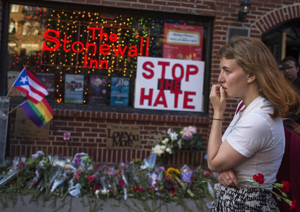 A woman in New York cries and holds flowers in front of a makeshift memorial to remember the victims of a mass shooting in Orlando, Fla. (Andres Kudacki/AP)