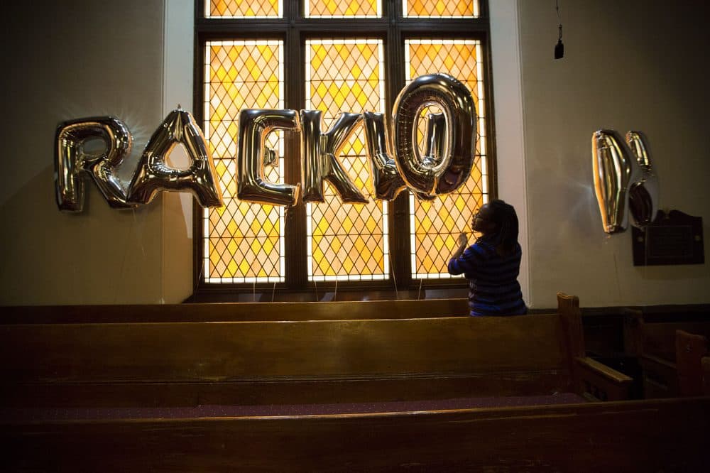 Raekwon Brown's cousin, sets up balloons spelling out his name before his funeral ceremony Thursday. (Jesse Costa/WBUR)