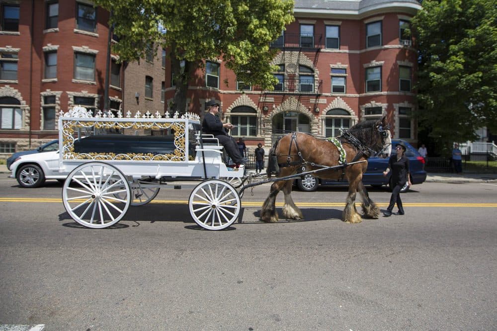 Raekwon Brown's casket is driven down Warren Street in a horse-drawn carriage to his burial site at Oak Lawn Cemetery in Roslindale. (Jesse Costa/WBUR)