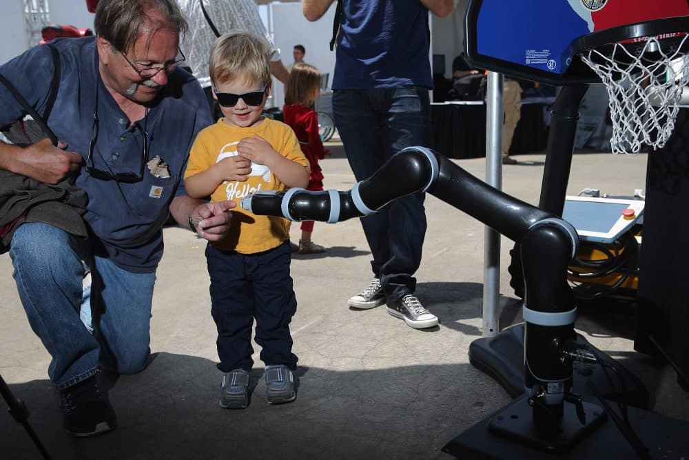 Two-year-old Hunter Kleimo and his grandfather Mike Kleimo interact with a Clearpath Robotics robot at the Defense Advanced Research Projects Agency Robotics Challenge Expo at the Fairplex June 5, 2015 in Pomona, California. (Chip Somodevilla/Getty Images)