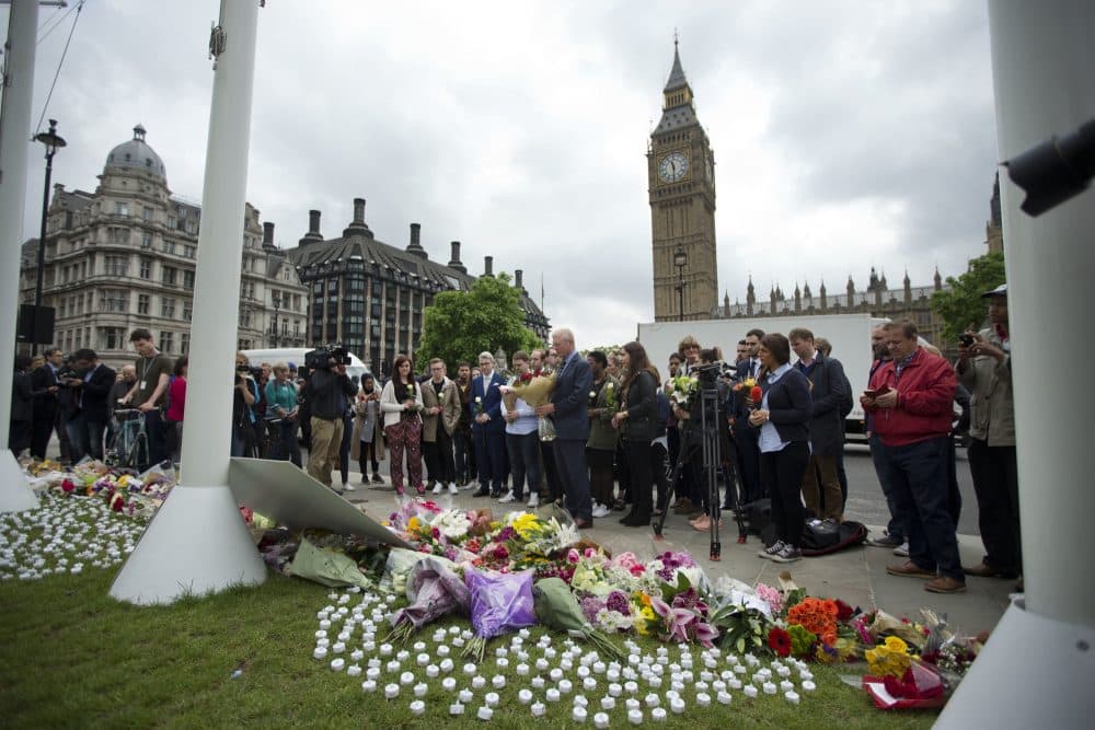 Staff from Britain's opposition Labour Party stand together before placing floral tributes for their colleague Jo Cox, the 41-year-old British Member of Parliament shot to death yesterday in northern England, on Parliament Square outside the House of Parliament in London, Friday, June 17, 2016. (AP Photo/Matt Dunham)