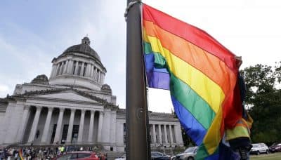A state worker unfurls a rainbow flag in front of the Washington state Capitol to prepare it to be raised and then lowered to half-staff to mark last weekend's mass shooting at a central Florida nightclub.Wednesday, June 15, 2016, in Olympia, Wash. A gunman wielding an assault-type rifle and a handgun opened fire inside Pulse, a crowded gay nightclub in Orlando, Florida, early Sunday, leaving at least 49 people dead in the worst mass shooting in modern U.S. history. (AP Photo/Elaine Thompson)