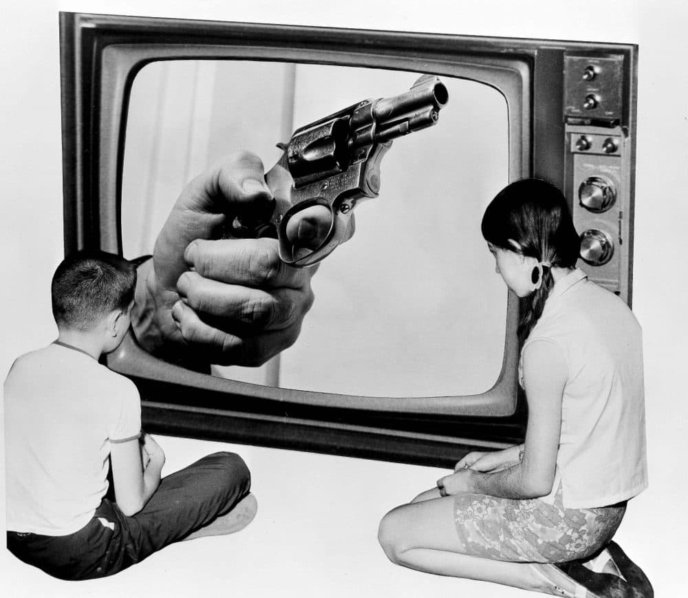 Steve Almond: There is a more direct means of making your voice heard on gun violence in this country: Divest from the gun industry. Pictured: A composite of two children looking at a hand holding a gun on a TV screen, in New York, June 21, 1968. The original caption asked: &quot;Will we ever see the day when the fist clenched around the grip of a deadly weapon will cease being shown as 'part of the times' we live in?&quot; Almost 48 years to the day later, America has yet to solve its problem of gun violence. (Bob Wands/AP)