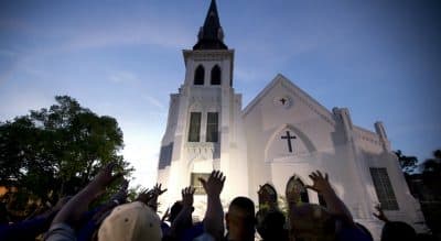 Mark Edington: &quot;We don’t need more weapons to make ourselves safer. We need more places of pilgrimage. And we need to go, not as tourists, but as pilgrims — people willing to be changed.&quot; Pictured: A crowd of people in prayer outside the Emanuel AME Church, Friday, June 19, 2015. Nine people were shot to death at the church two days prior. (AP Photo/Stephen B. Morton)