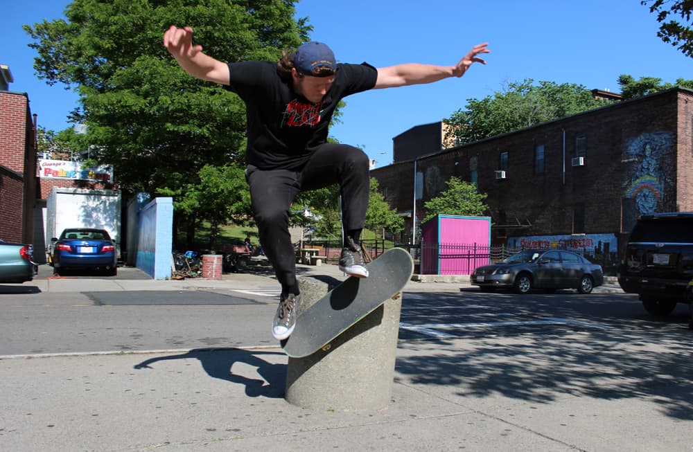 Fancy Lad owner, Nick Murray, does a wallride on a concrete bollard. (Michael Hagerty for WBUR)