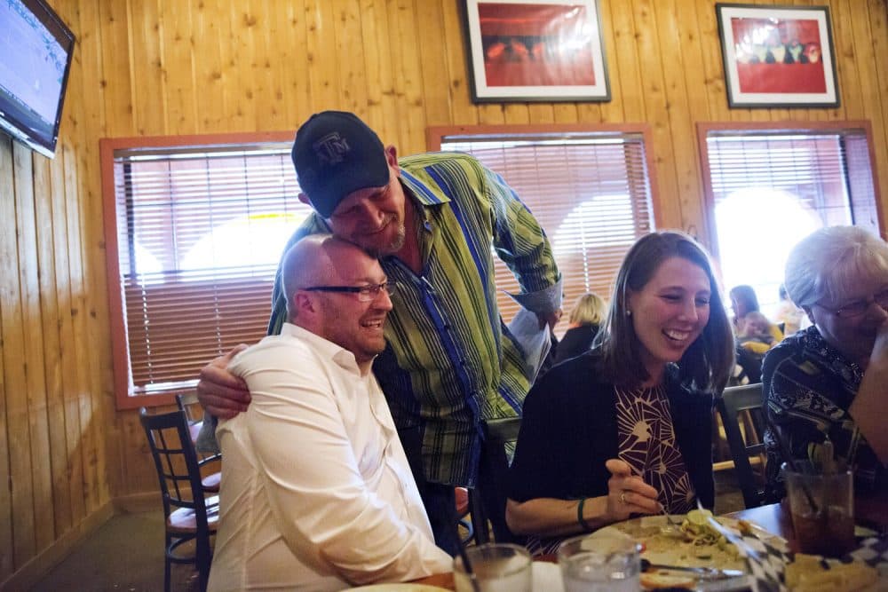 Richie Clendenen, lead pastor at Christian Fellowship Church, left, is embraced by congregant Judd Deaton, after a service while dining with his wife Jenny at a restaurant in Benton, Ky.(David Goldman/AP)
