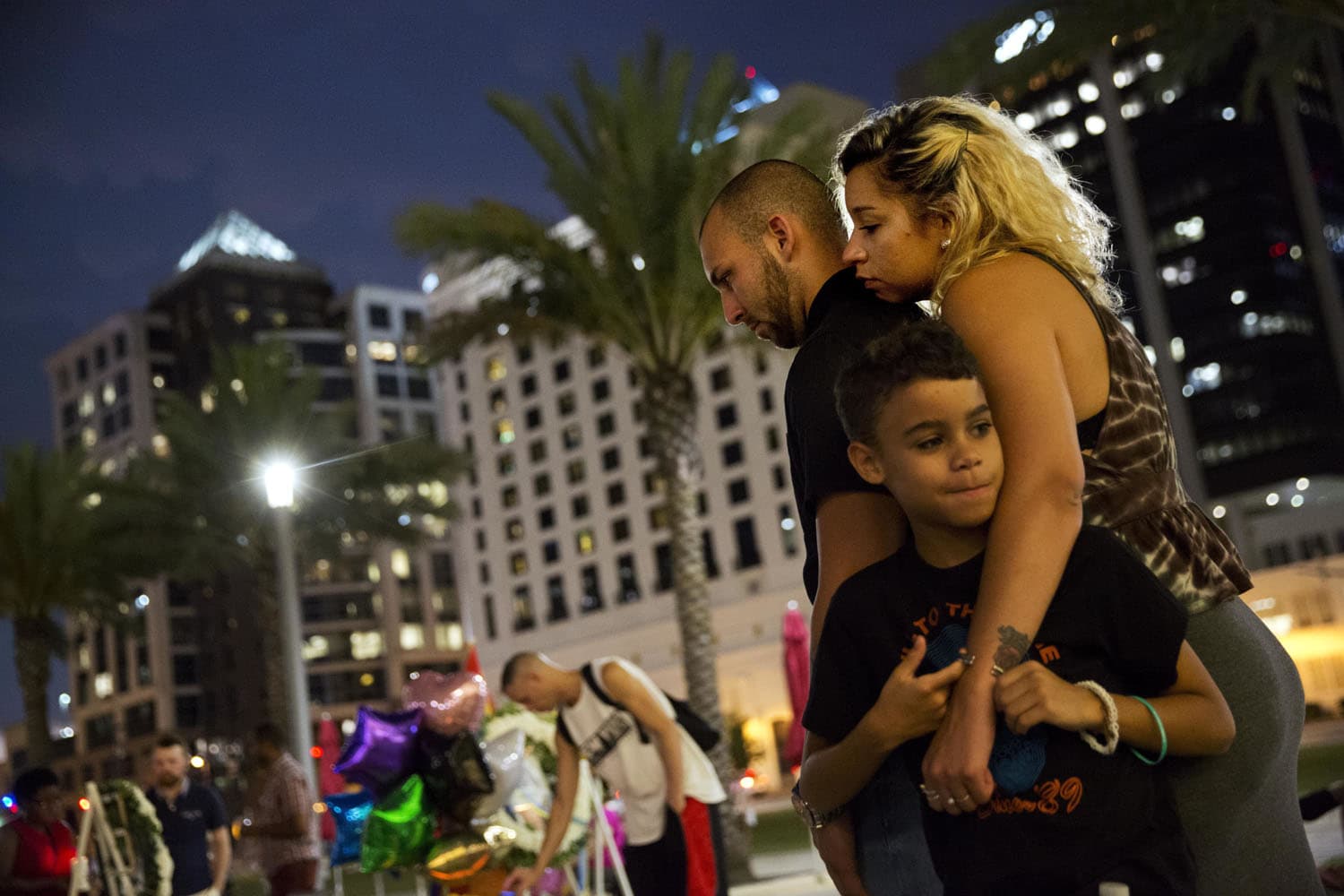 Jennifer Johnson, right, leans on her boyfriend Jeansem Sambolin while standing with her son Tyrone Clarke, 8, as they visit a makeshift memorial for the victims of the mass shooting at the Pulse Orlando nightclub Tuesday, June 14, 2016, in Orlando, Fla. David Goldman / AP)