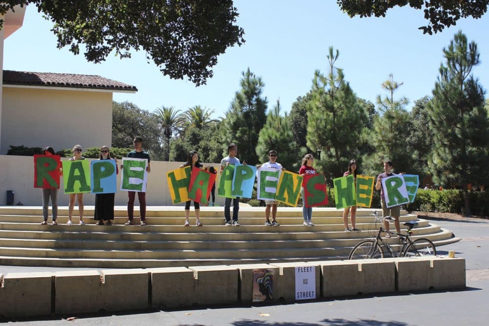 In this Sept. 16, 2015 photo provided by Tessa Ormenyi, students hold up a sign about rape at White Plaza during New Student Orientation on the Stanford University campus in Stanford, Calif.  (Tessa Ormenyi / AP) 