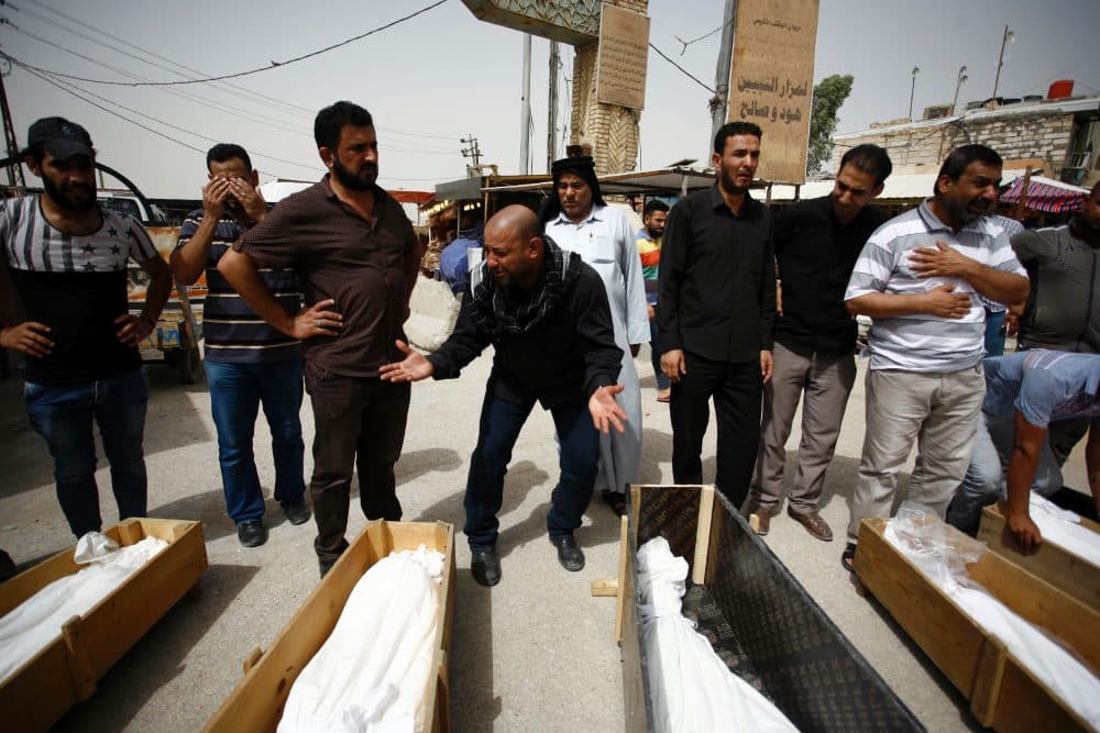 Iraqi men mourn over bodies after they lost five members of their family in a suicide bombing that ripped through Baghdad's busy shopping district of Karrada, during their funeral in the holy Iraqi city of Najaf on July 3, 2016. 
The blast hit the Karrada district early in the day as the area was packed with shoppers ahead of this week's holiday marking the end of the Muslim fasting month of Ramadan, killing at least 75 people in the deadliest single attack this year in Iraq's capital. (HAIDAR HAMDANI/AFP/Getty Images)