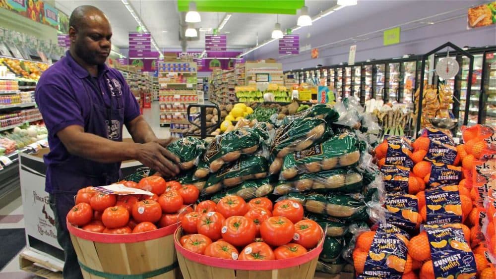 Produce manager Nate Sumpter arranges fresh fruits and vegetables at Fare & Square grocery in Chester. (Emma Lee/WHYY)
