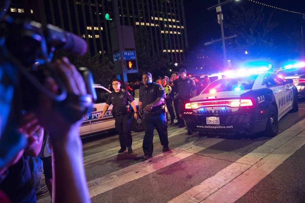 Bystanders stand near pollice baracades following the sniper shooting in Dallas on July 7, 2016. (Laura Buckman/AFP/Getty Images)