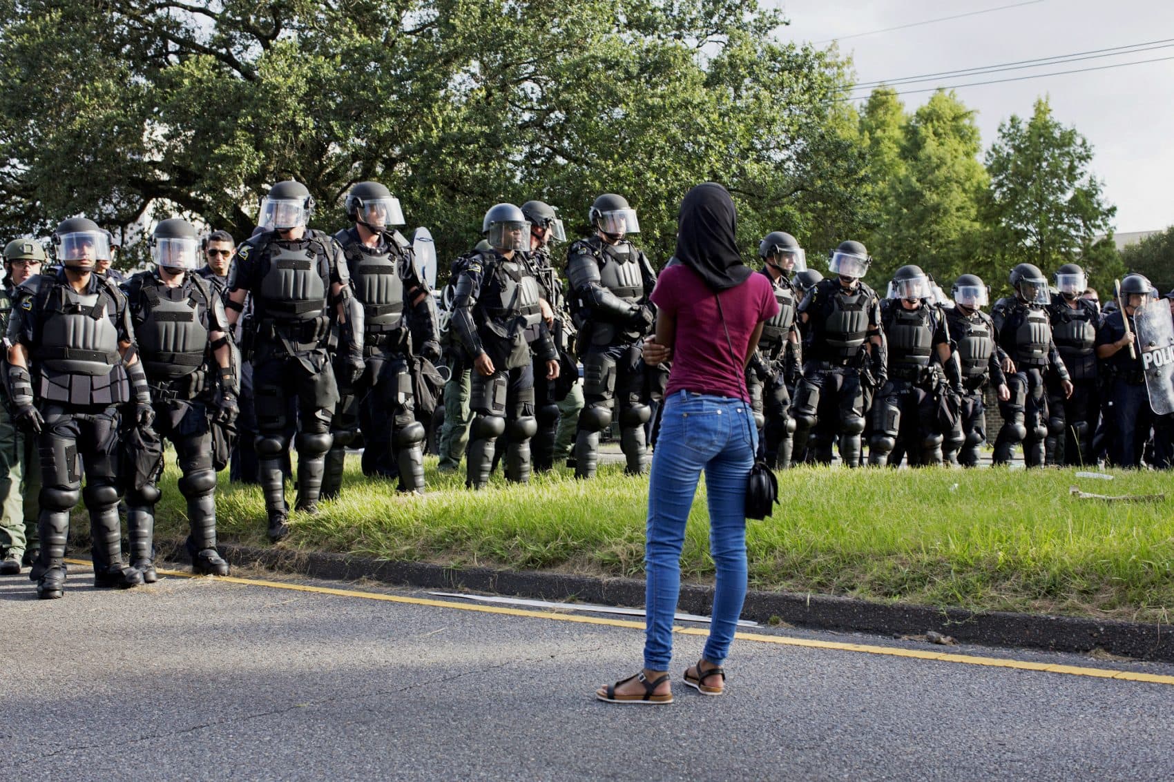 A protester watches as police in riot gear clear the street of protesters in front of the Baton Rouge Police Department headquarters in Baton Rouge, La., Saturday, July 9, 2016. (Max Becherer/AP)
