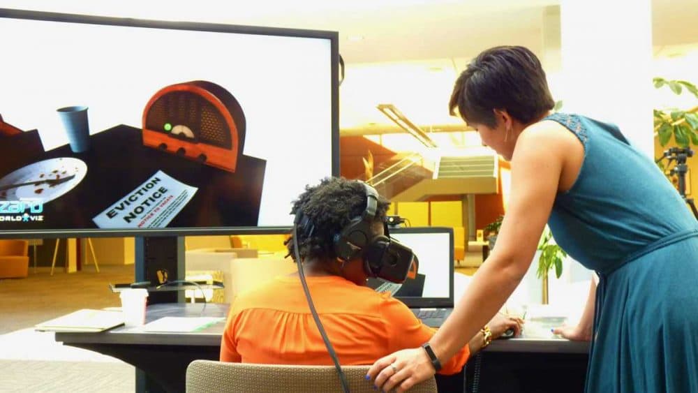 Vanessa Farrell, a program associate at the Robert Wood Johnson Foundation, tries out an empathy-aimed virtual reality experience. Elise Ogle, from Stanford’s Virtual Human Interaction Lab, helped design the program. (Todd Bookman/WHYY)
