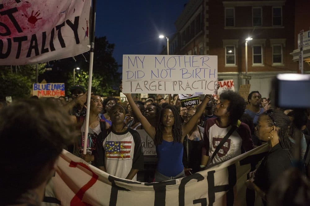A woman holds up a sign in protest of police brutality at a rally in Boston that drew a significant crowd Wednesday night. (Joe Difazio/WBUR)