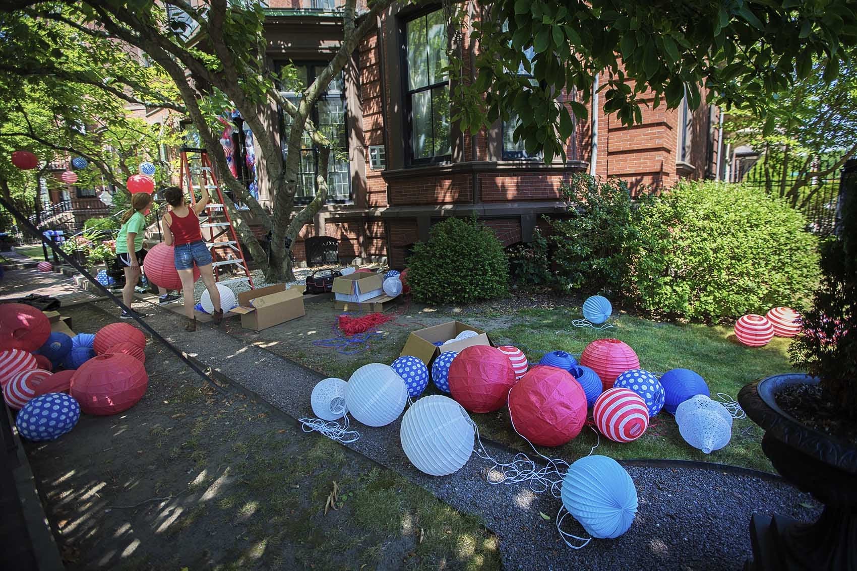 Volunteers set up red, white and blue lanterns for the French Cultural Center's annual Bastille Day celebration on Friday. (Jesse Costa/WBUR)
