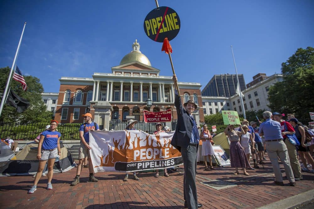 Tim Clancy, of West Roxbury, holds up a no pipeline sign in front of the State House Monday. (Jesse Costa/WBUR)