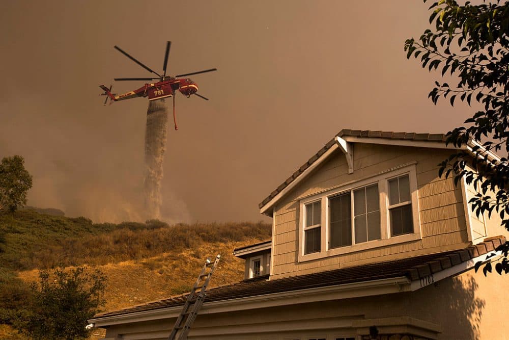 A firefighting helicopter makes a water drop near homes at the Sand Fire on July 24, 2016 in Santa Clarita, California. Triple-digit temperatures and dry conditions are fueling the wildfire, which has burned across at least 32,000 acres so far and is only 10% contained. (David McNew/Getty Images)