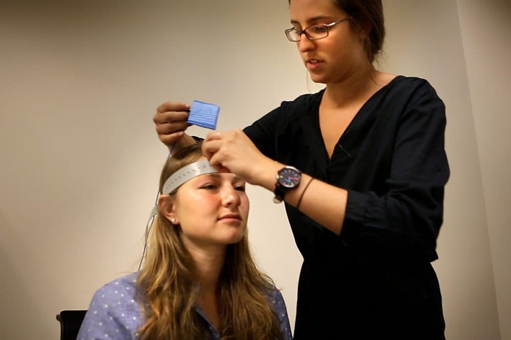 In this 2014 file photo, Ann Carroll fits nodes to Sarah Beth Spitzer’s forehead in preparation for transcranial direct current stimulation testing at the Center for Brain Science at Harvard University. (Jesse Costa/WBUR)