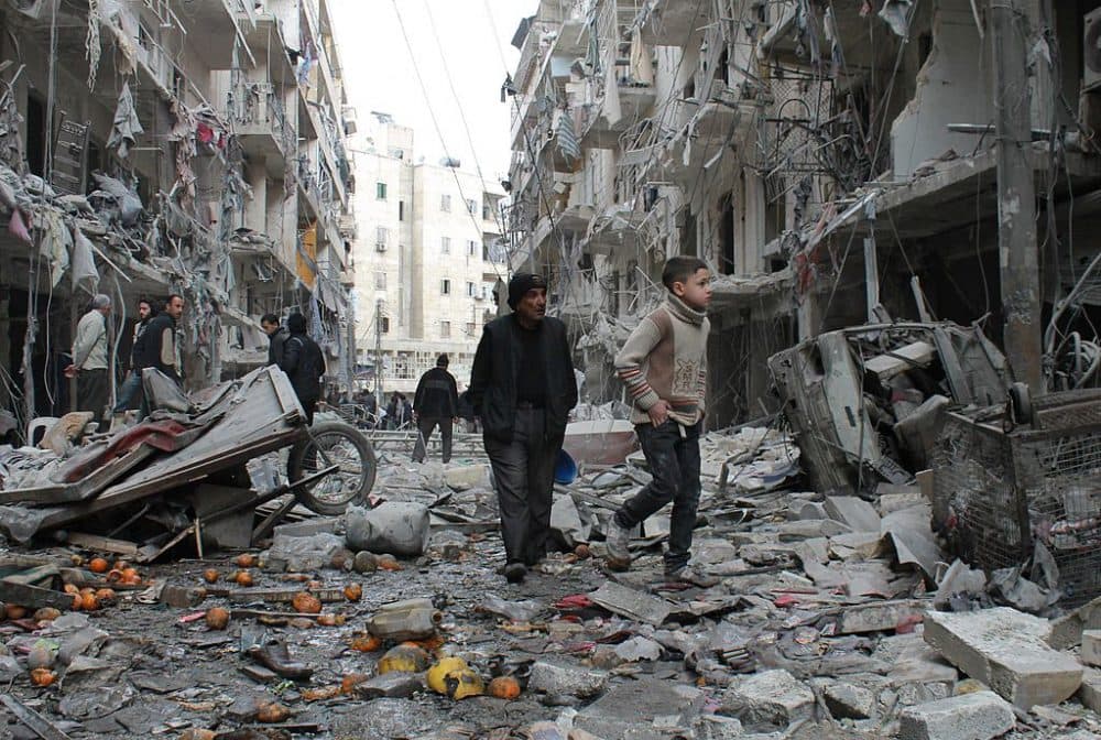 An elderly Syrian man and a child walk amidst debris in a residential block reportedly hit by an explosives-filled barrel dropped by a government forces helicopter on March 18, 2014 in Aleppo. (Baraa Al-Halabi/AFP/Getty Images)