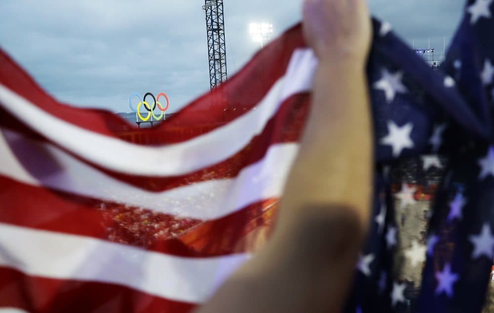 The Olympic rings are seen atop the beach volleyball venue as spectators wave an American flag at the 2016 Summer Olympics in Rio de Janeiro, Brazil, Monday, Aug. 8, 2016. (David Goldman/AP)

