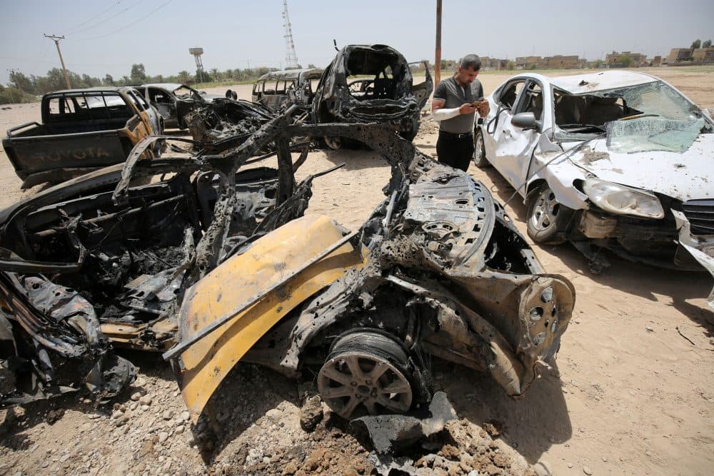 An Iraqi man stands next to damaged cars as he inspects the site of a suicide bomb attack, claimed by the Islamic State group, at a checkpoint leading to the Husseiniyah area, northeast of the capital Baghdad on July 13, 2016. (Ahmad Al-Rubaye/AFP/Getty Images)