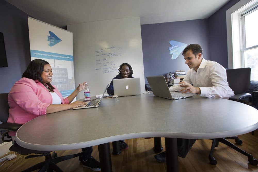 Melissa James, Kofi Callender and Gilad Rozensweig, founder of Smarter in the City, talk in a conference room at the accelerator's Roxbury location. (Jesse Costa/WBUR)