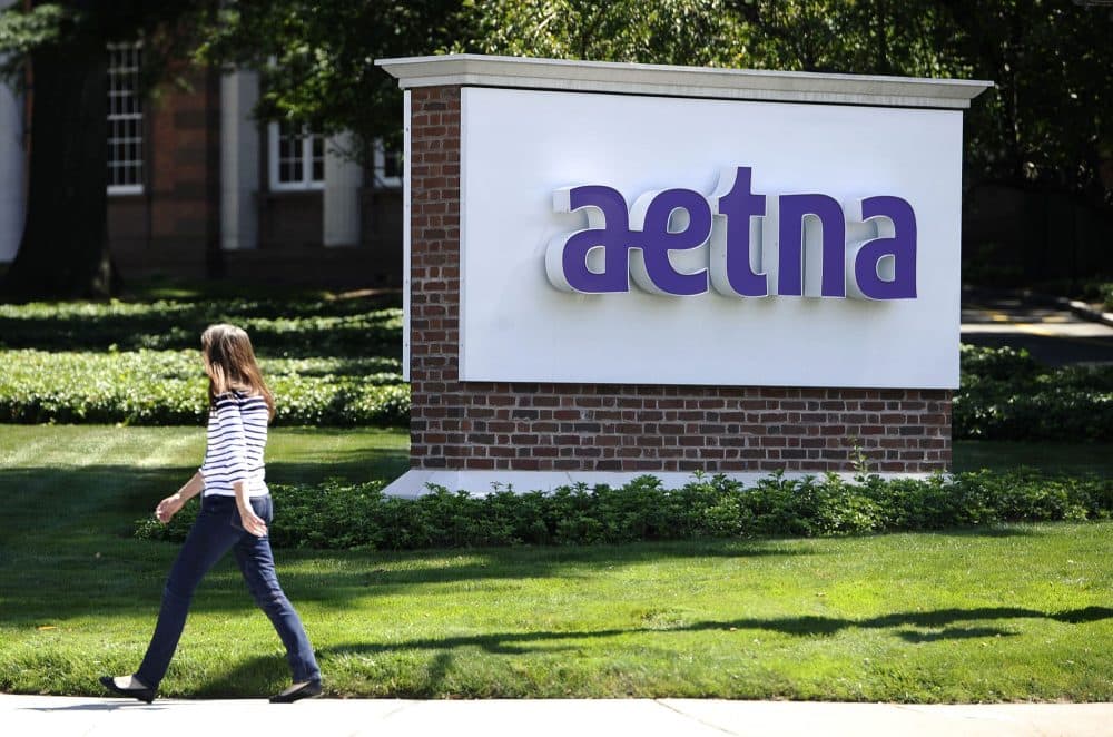In this Tuesday, Aug. 19, 2014, file photo, a pedestrian walks past a sign for health insurer Aetna Inc., at the company headquarters in Hartford, Connecticut. (Jessica Hill/AP)