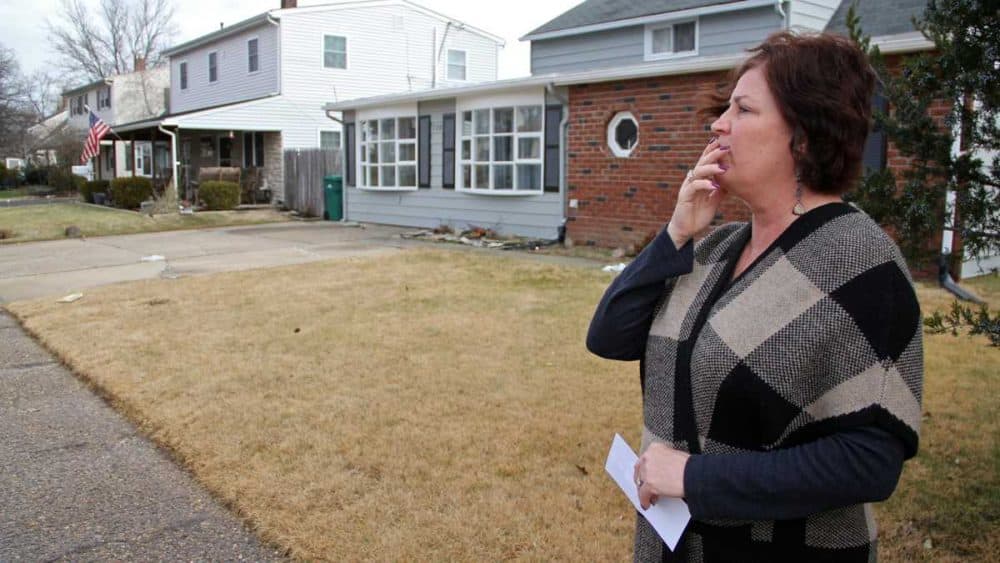 Debbie Fleming, holding a list of nine recovery homes in her neighborhood in Levittown, Pennsylvania, pauses outside a recovery home on Goldengate Road. (Emma Lee/WHYY)
