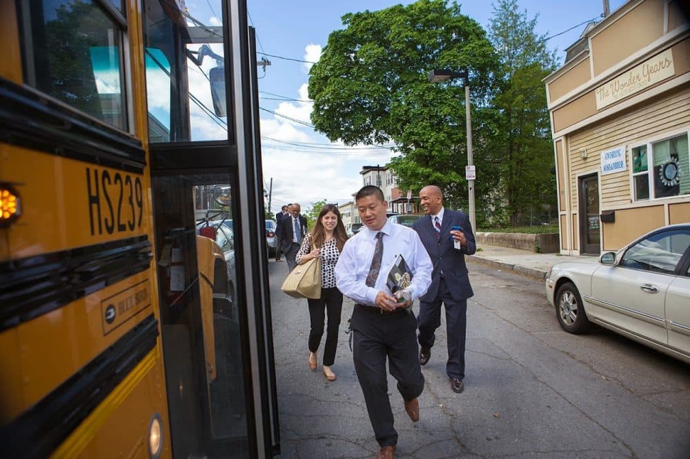 Boston Public Schools Superintendent Tommy Chang, center, walks toward a school bus in May 2015. (Jesse Costa/WBUR file photo)