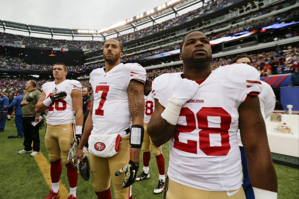 San Francisco 49ers quarterback Colin Kaepernick (7) stands with teammates during the playing of the national anthem before a 2014 NFL football game. (Julio Cortez/AP)